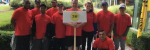 All T-R staff wearing red t-shirts in front of a building holding up a white T-R sign for the Corporate Kids Challenge 2017