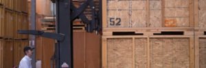 T-R employee wearing a baseball cap and moving storage crates using a red fork lift