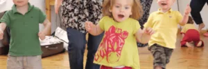 Children walking around with their moms in a classroom setting