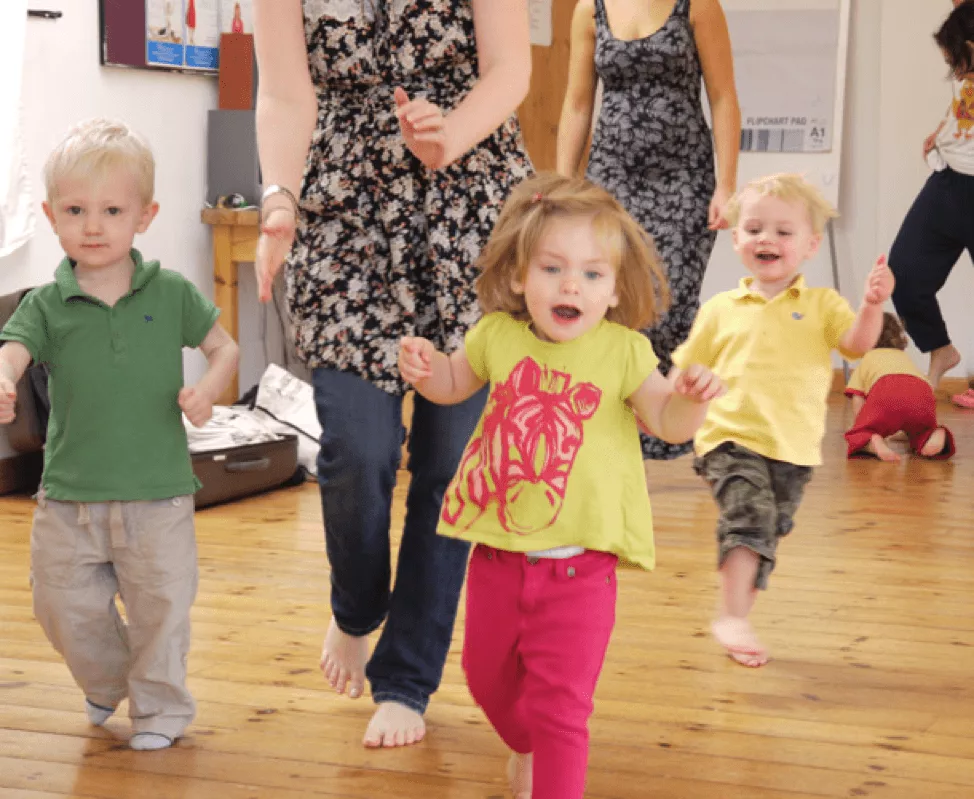 Children walking around with their moms in a classroom setting