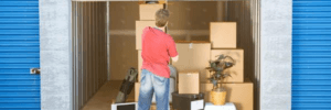 Man, wearing a red top and blue jeans is in front of a storage unit, storing office files, boxes and computer equipment