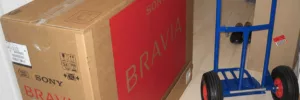 Tippet Richardson moving a Sony Bravia 40-inch LCD in a brown box with a small blue trolley