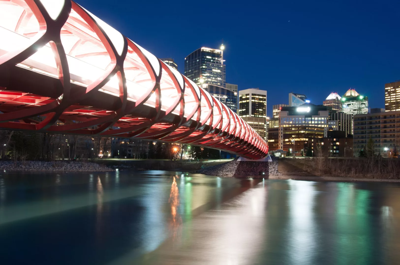 Night time city skyline view of the pedestrian bridge that spans the bow river in Calgary, Alberta, Canada